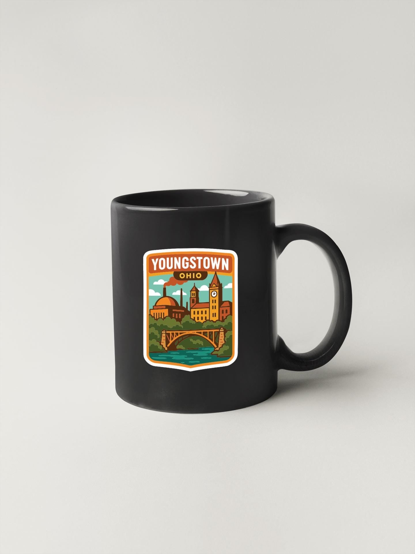 A black coffee mug with a sticker depicting the town of Youngstown, Ohio.