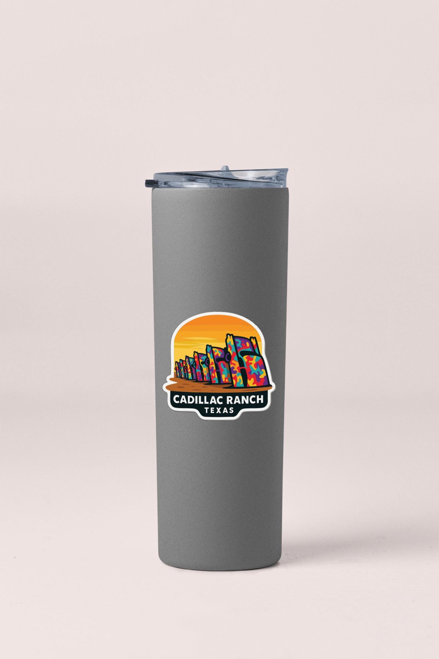 A gray insulated tumbler with a colorful sticker depicting a sunset over a city skyline.