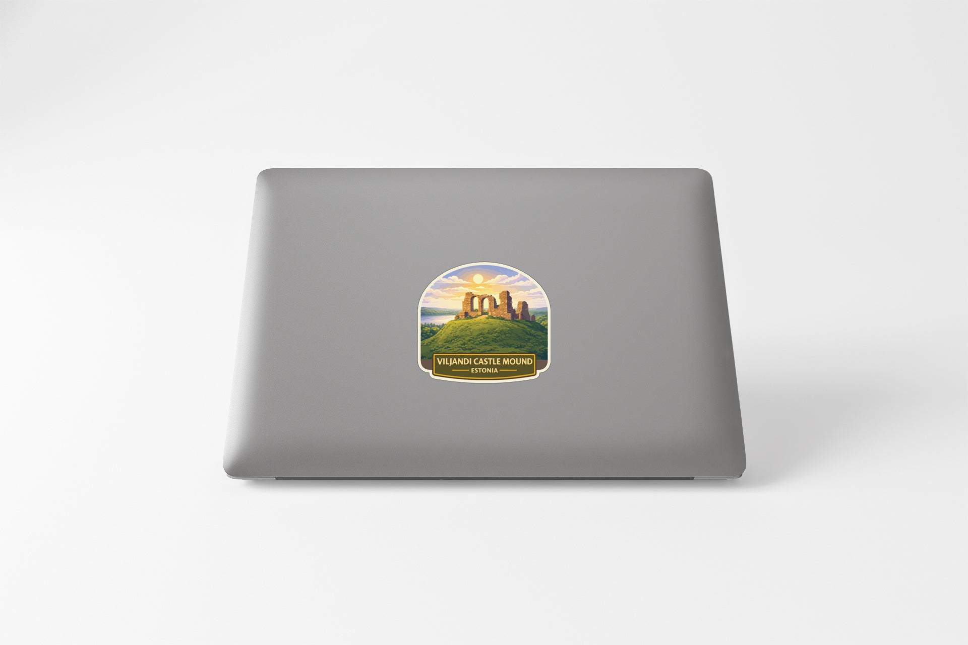 a sticker on the back of a laptop, depicting a castle or monument surrounded by a landscape with a sunset or sunrise in the background.