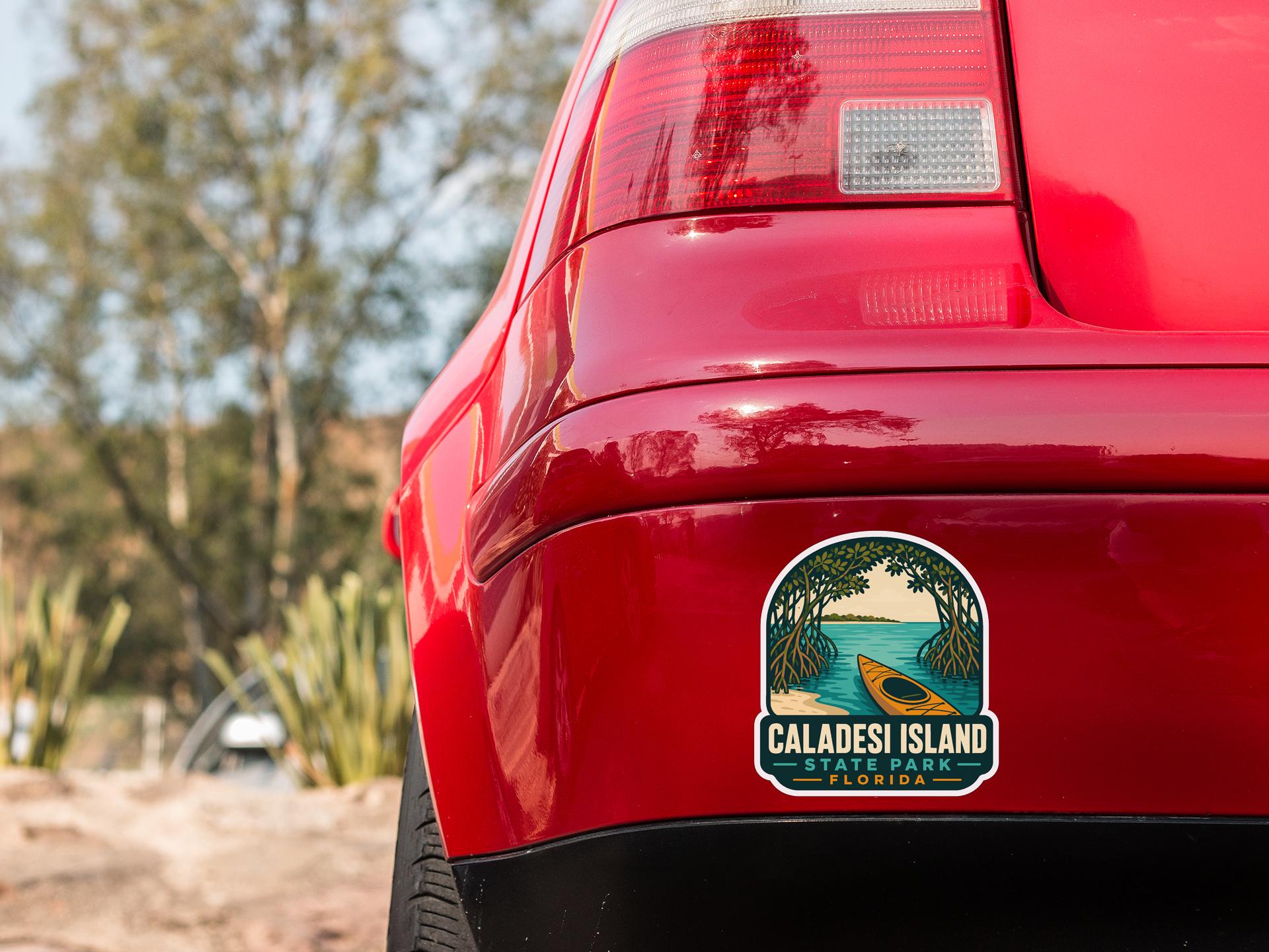the rear end of a red car with a sticker on the trunk that says "CALADESI ISLAND STATE PARK FLORIDA".