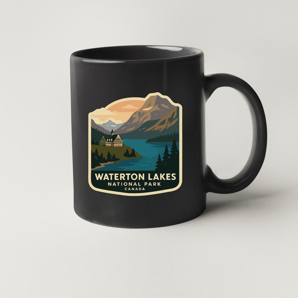 A black coffee mug with a graphic design depicting a scenic landscape featuring Waterton Lakes National Park in Canada.