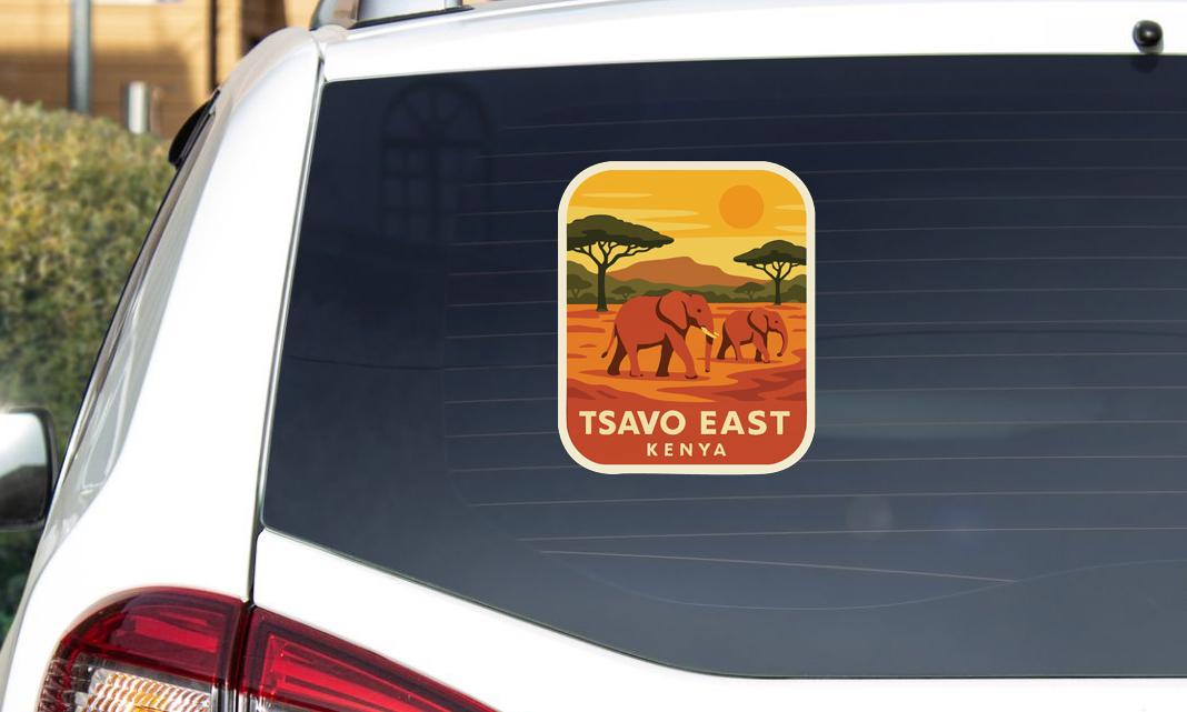A sticker on the rear window of a car, depicting an illustration of two elephants in a savanna landscape with a yellow sun in the sky.