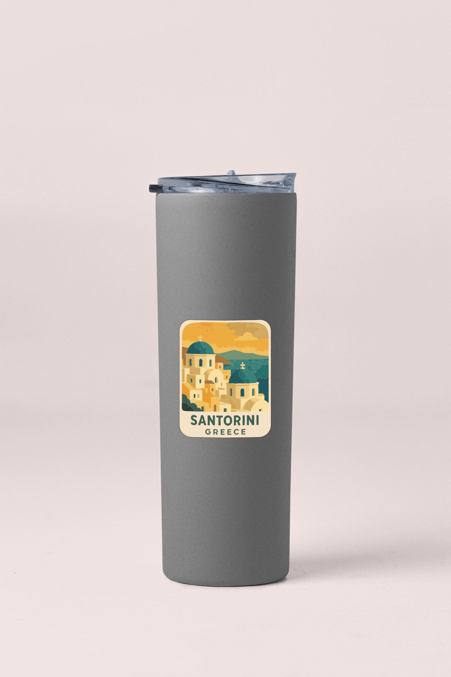 A gray insulated tumbler with a sticker depicting the Santorini Greek island.