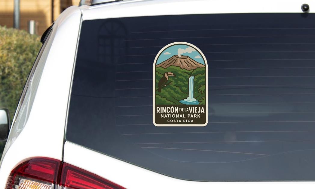 A sticker on the rear window of a vehicle, depicting a scenic landscape with a mountain, waterfall, and tropical vegetation.
