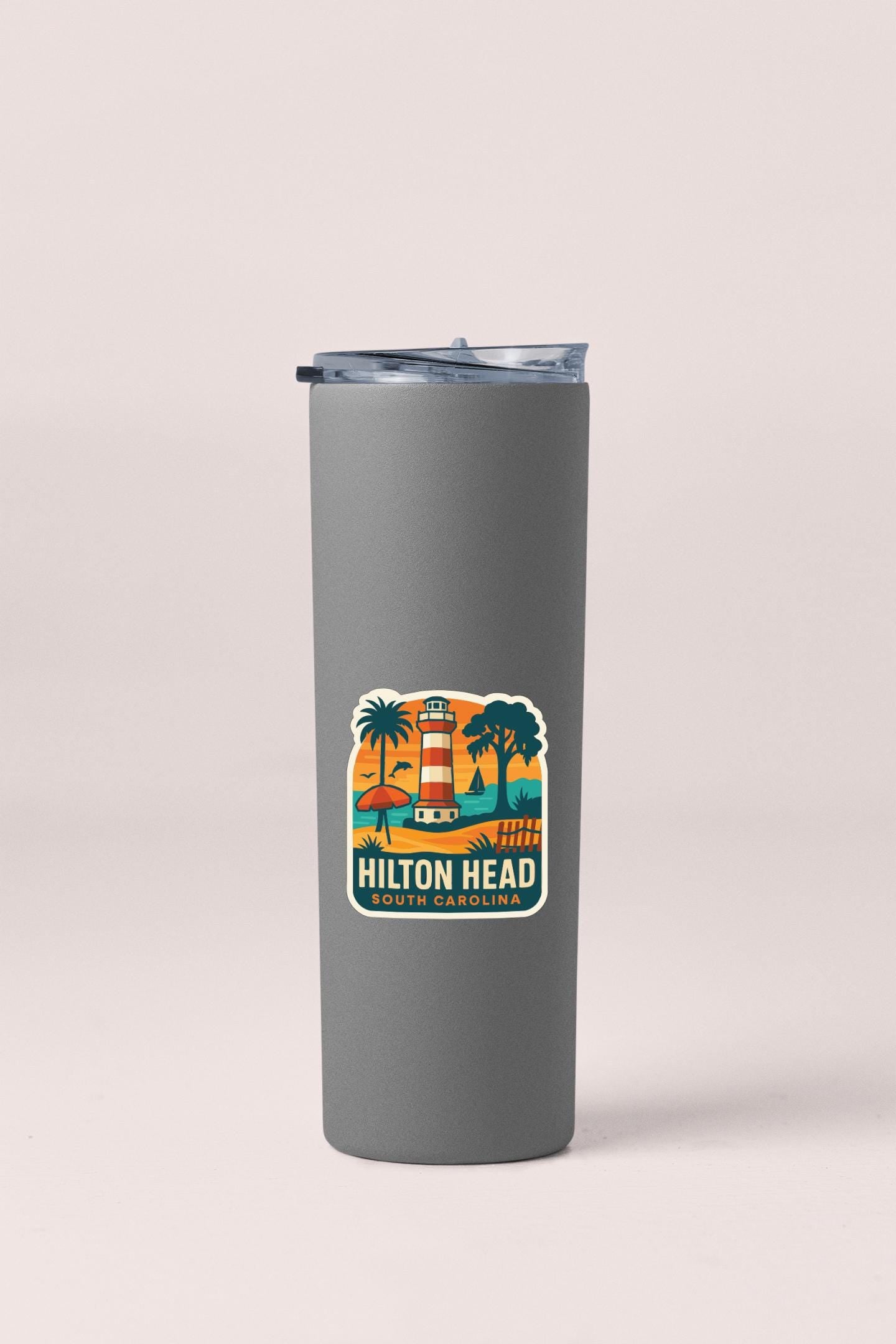 A gray insulated tumbler with a lid and a sticker depicting a lighthouse and palm trees.