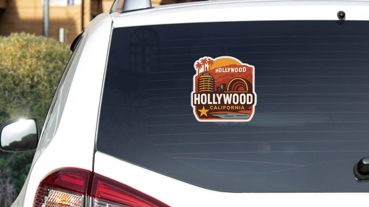 A sticker on the rear window of a white car, featuring the text "Hollywood California" and an illustration of the Hollywood sign.