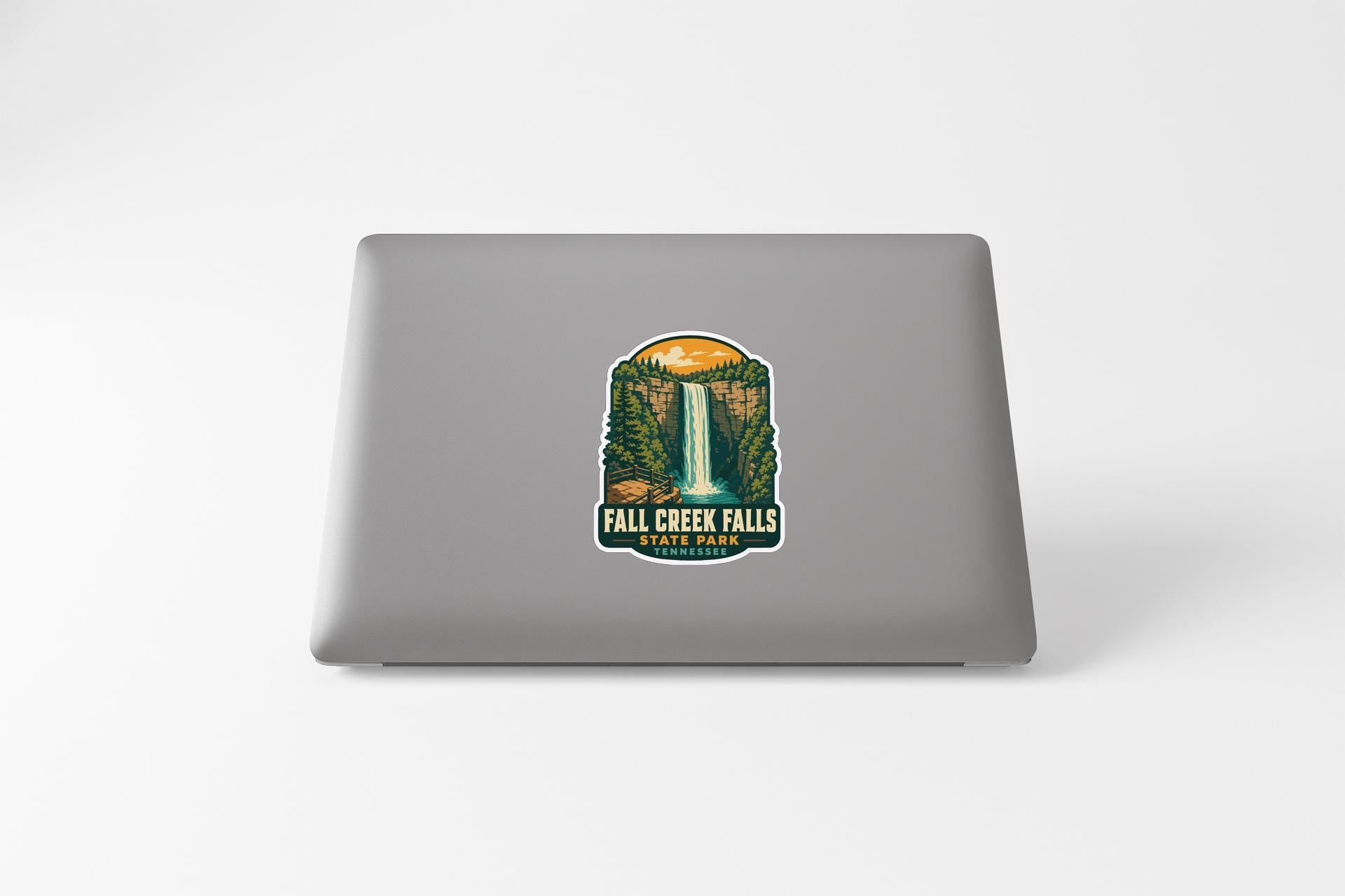 a sticker with a waterfall and forest on a laptop.