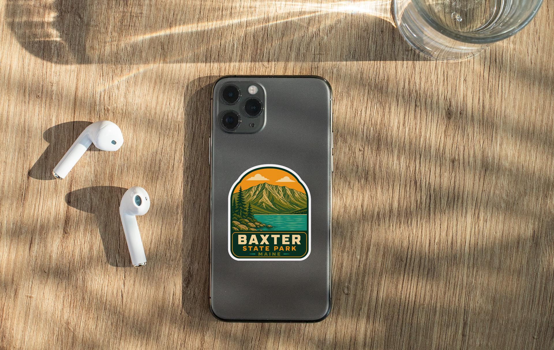 a smartphone with a sticker on it, placed on a wooden surface alongside a pair of white earbuds and a glass of water.