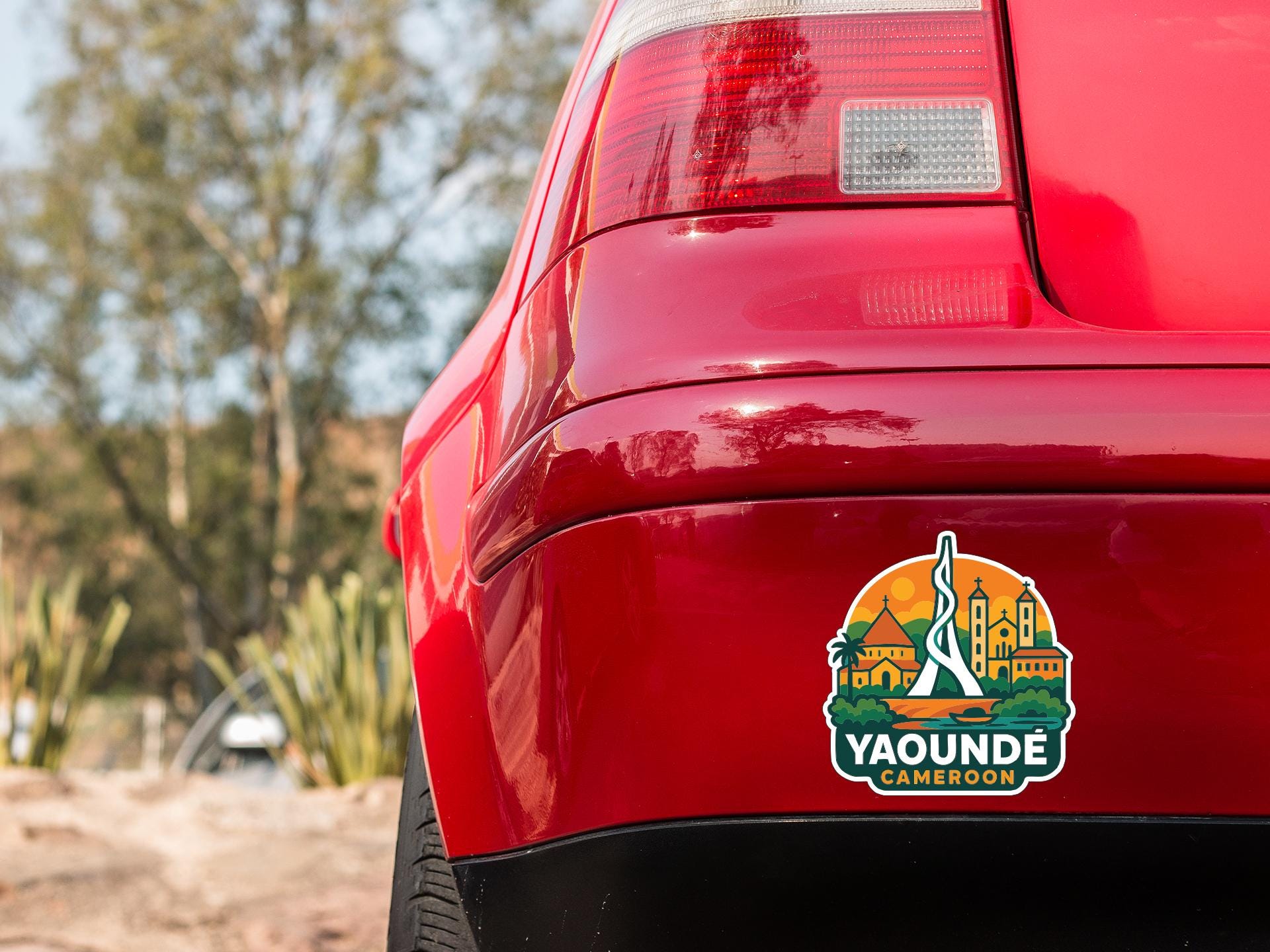 the rear end of a red car with a sticker on the trunk that says "Yaounde Cameroon".