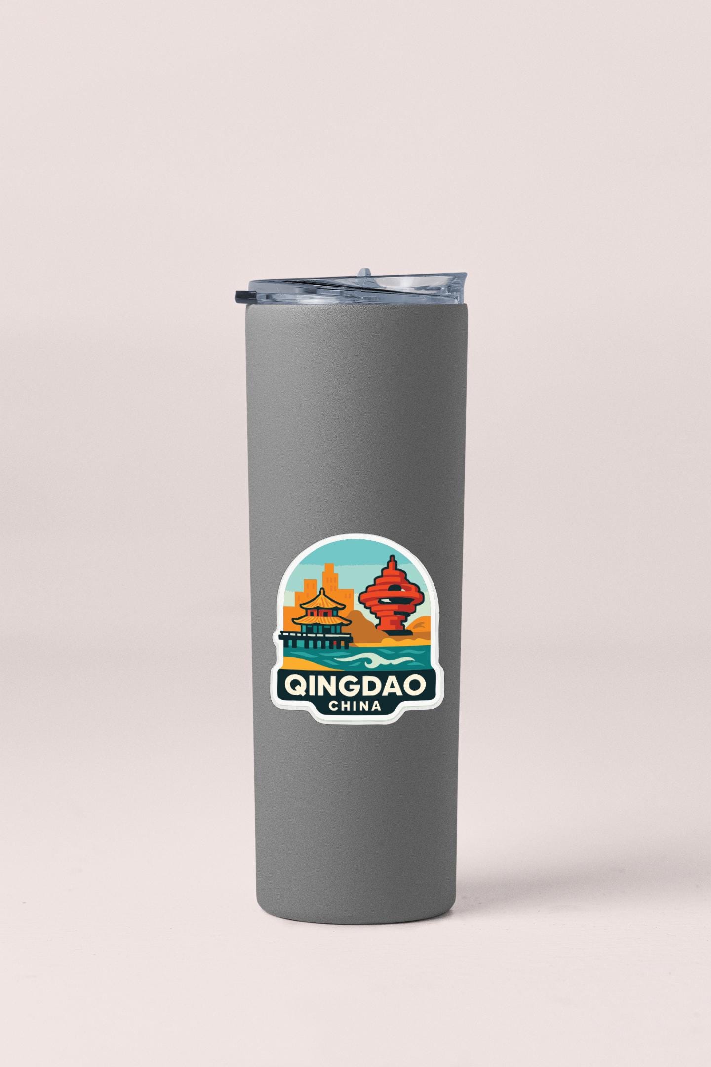 A gray insulated tumbler with a sticker depicting the city of Qingdao, China.