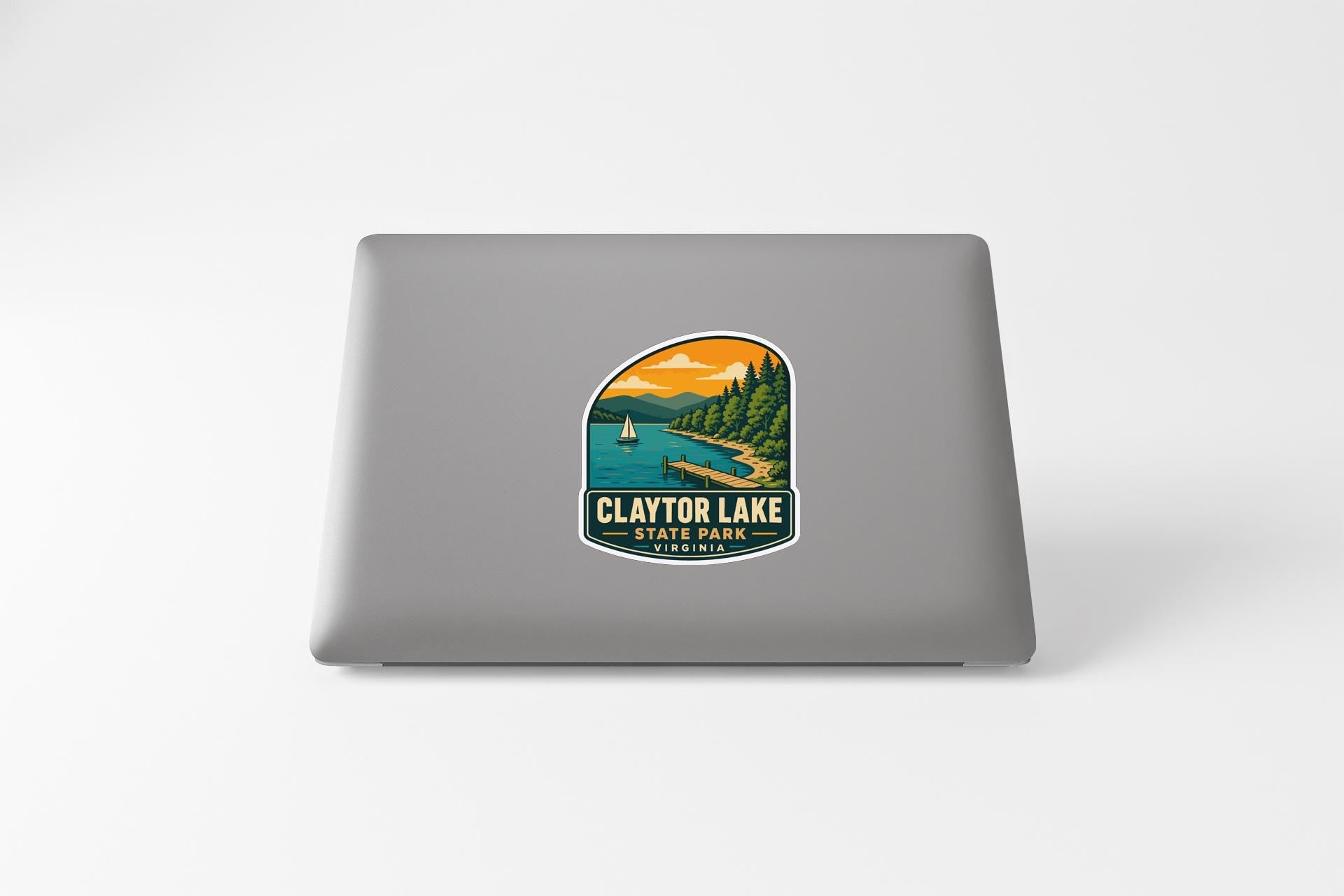 A sticker on the back of a laptop, depicting a scenic landscape with a lake, mountains, and a boat.