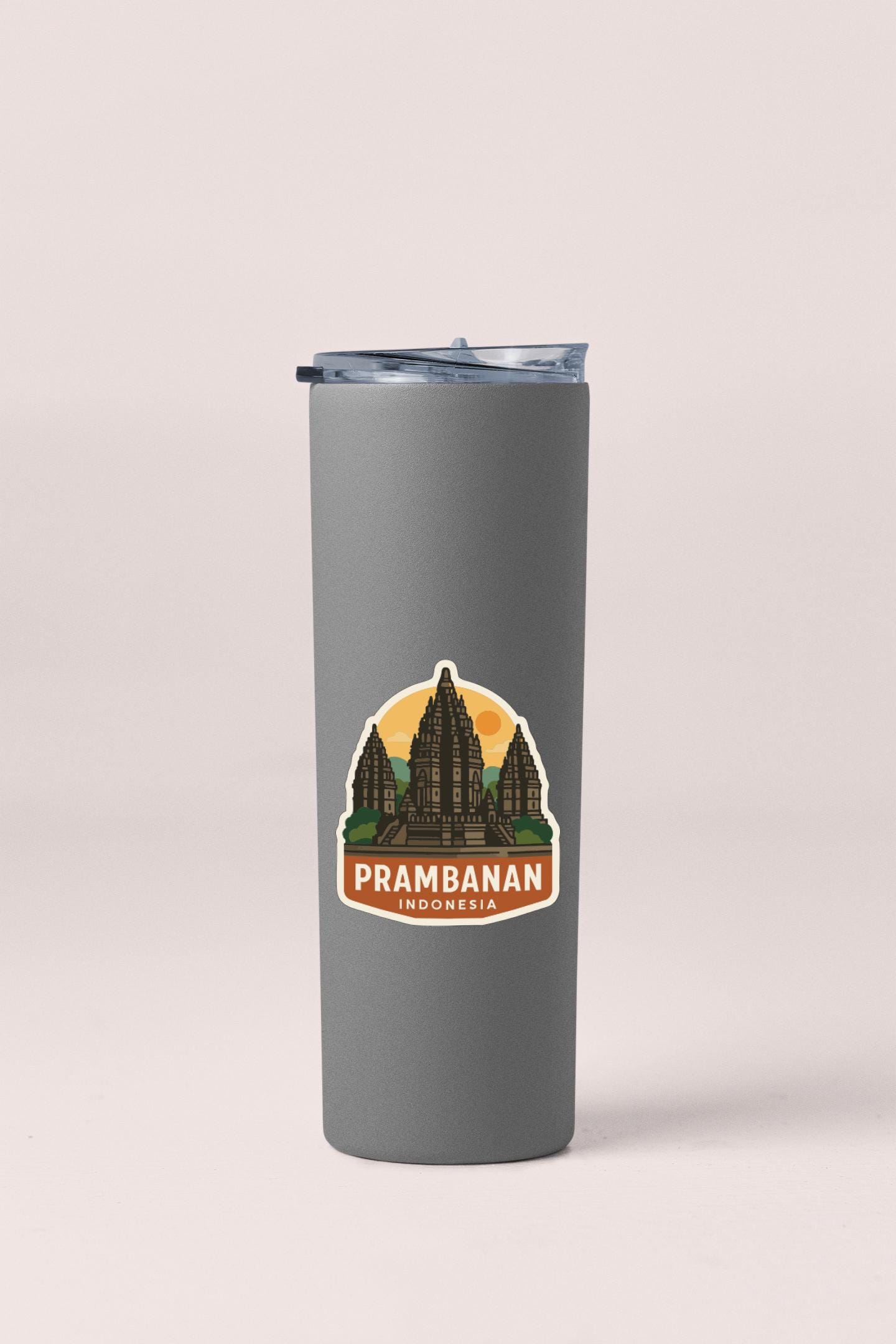 A gray insulated tumbler with a sticker depicting the Prambanan temple in Indonesia.