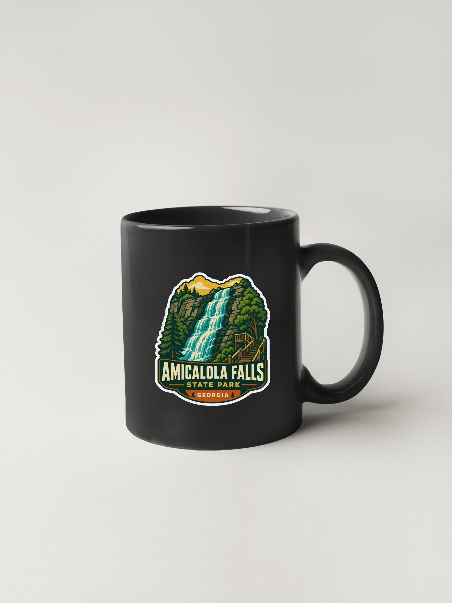 A black coffee mug with a graphic design depicting the falls of Amicalola Falls, a waterfall located in Georgia.