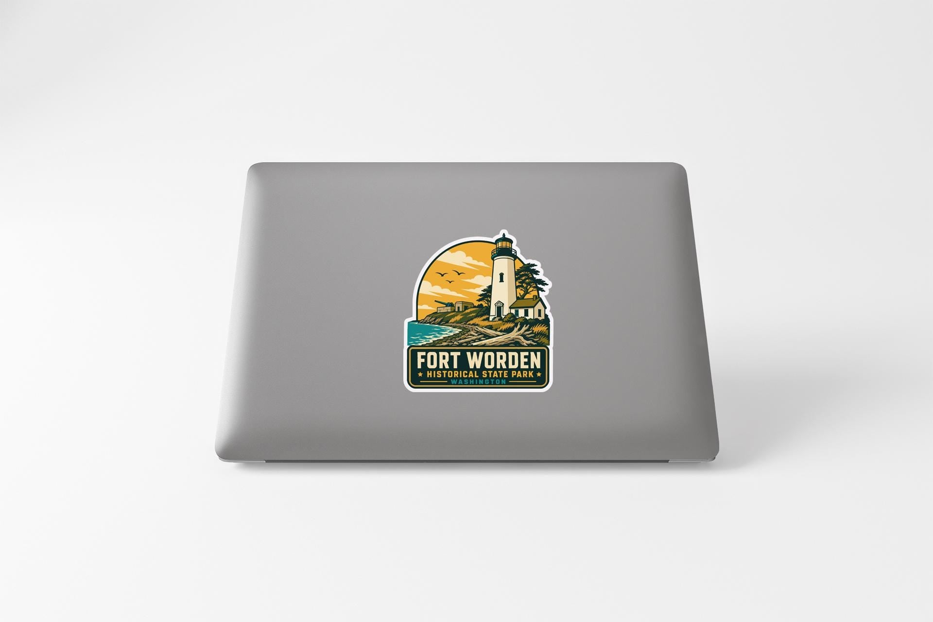 A sticker on the back of a laptop, depicting a lighthouse and a scenic landscape.