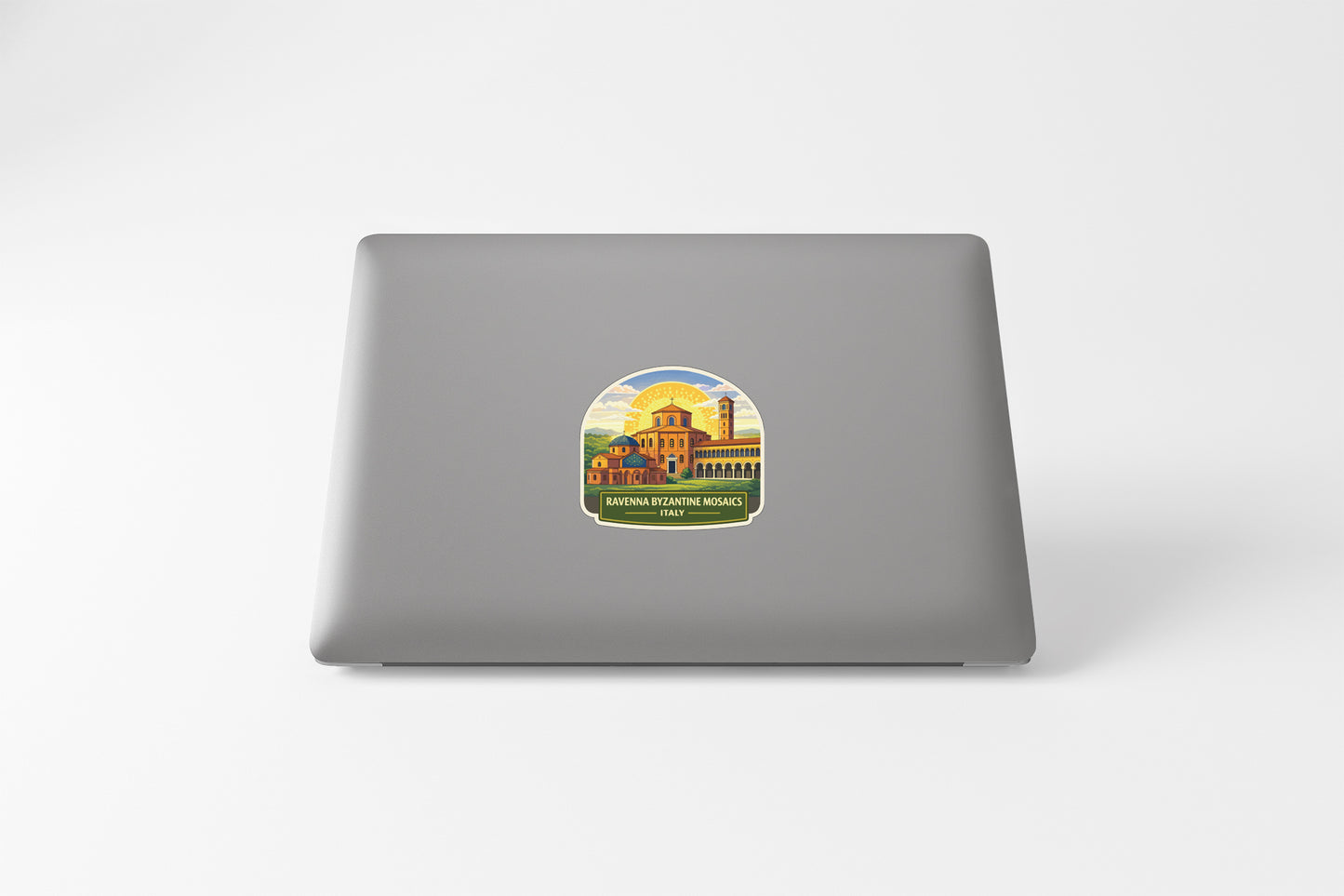 A sticker depicting a building with a yellow roof and a blue sky with clouds, placed on the back of a laptop computer.