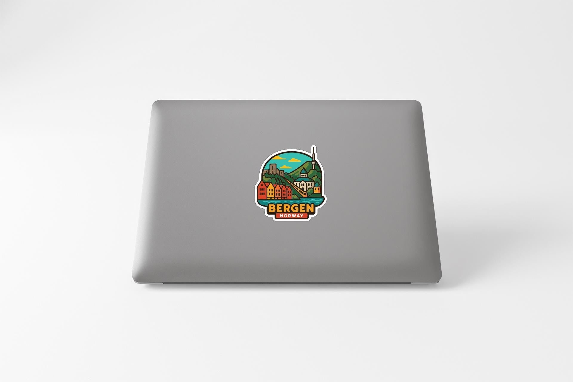 a sticker on the back of a laptop, depicting a scenic landscape with a mountain and a building.