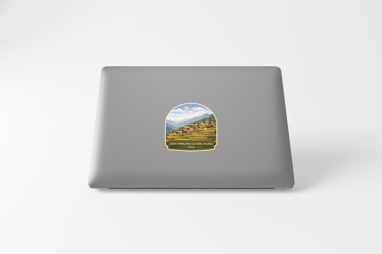 A sticker depicting a scenic landscape with mountains and buildings, placed on the back of a laptop computer.