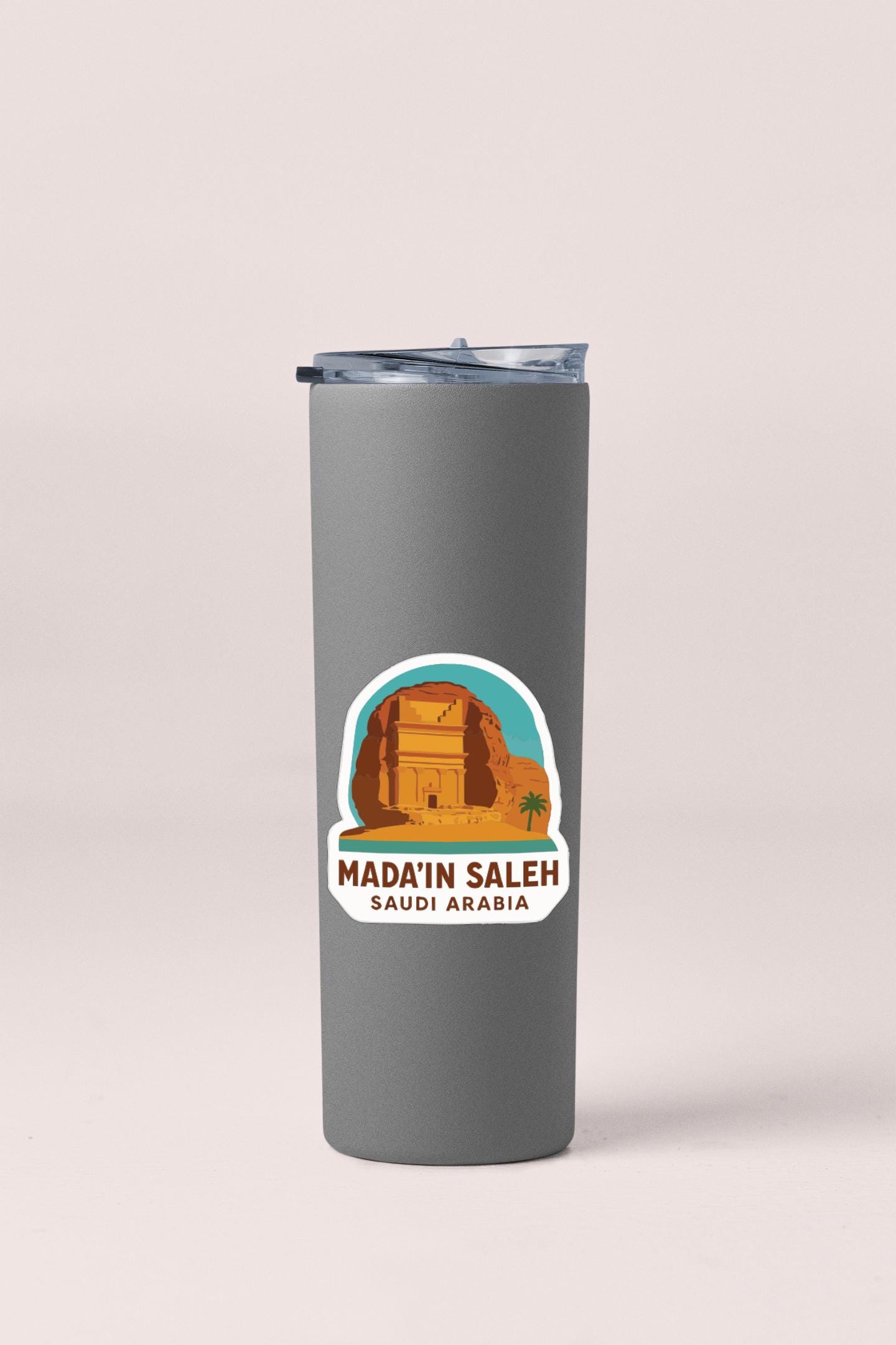 A gray tumbler with a sticker depicting the famous ancient city of Mada'in Saleh in Saudi Arabia.