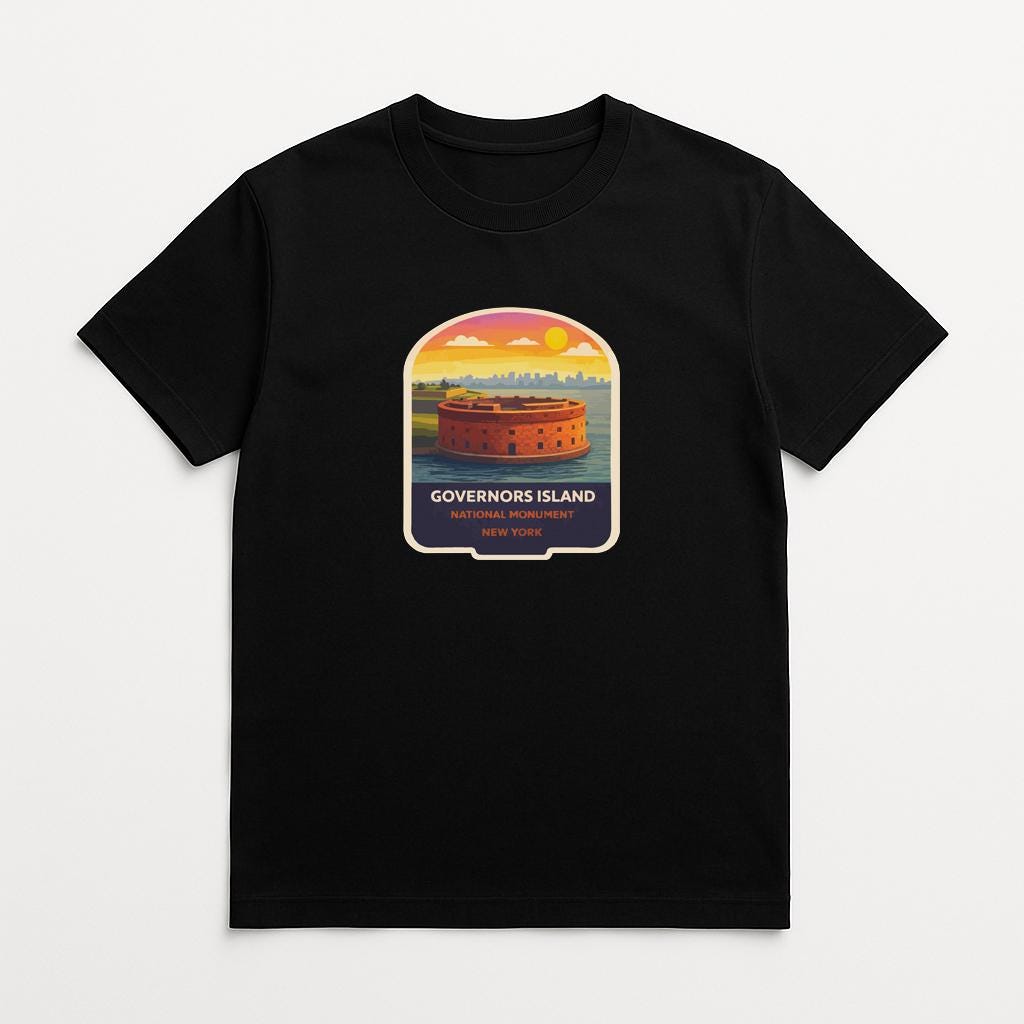 A black t-shirt with a graphic design depicting a castle or fort on a beach, with a sunset in the background.