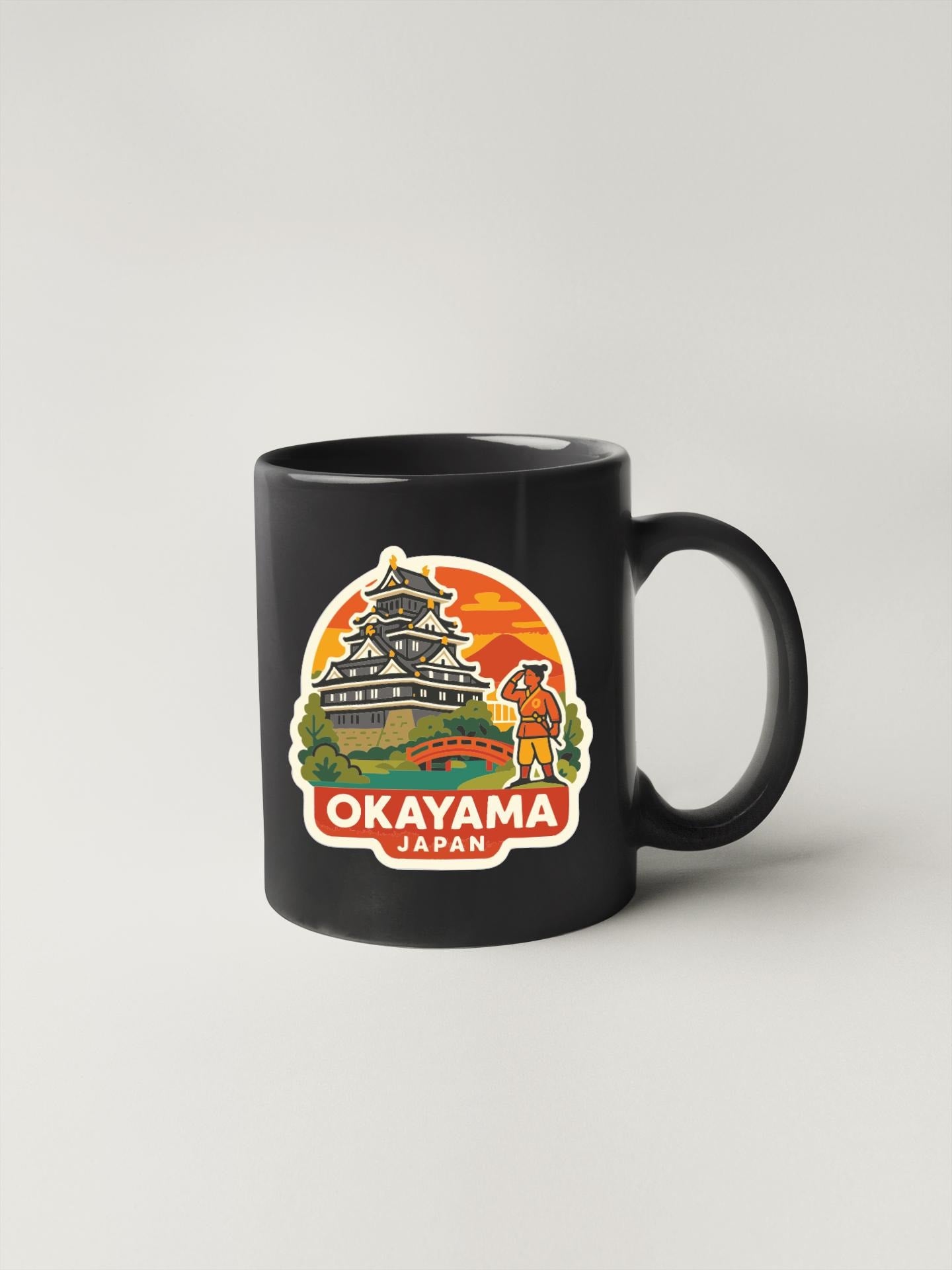 A black coffee mug with a colorful sticker depicting the Osaka Castle in Japan.