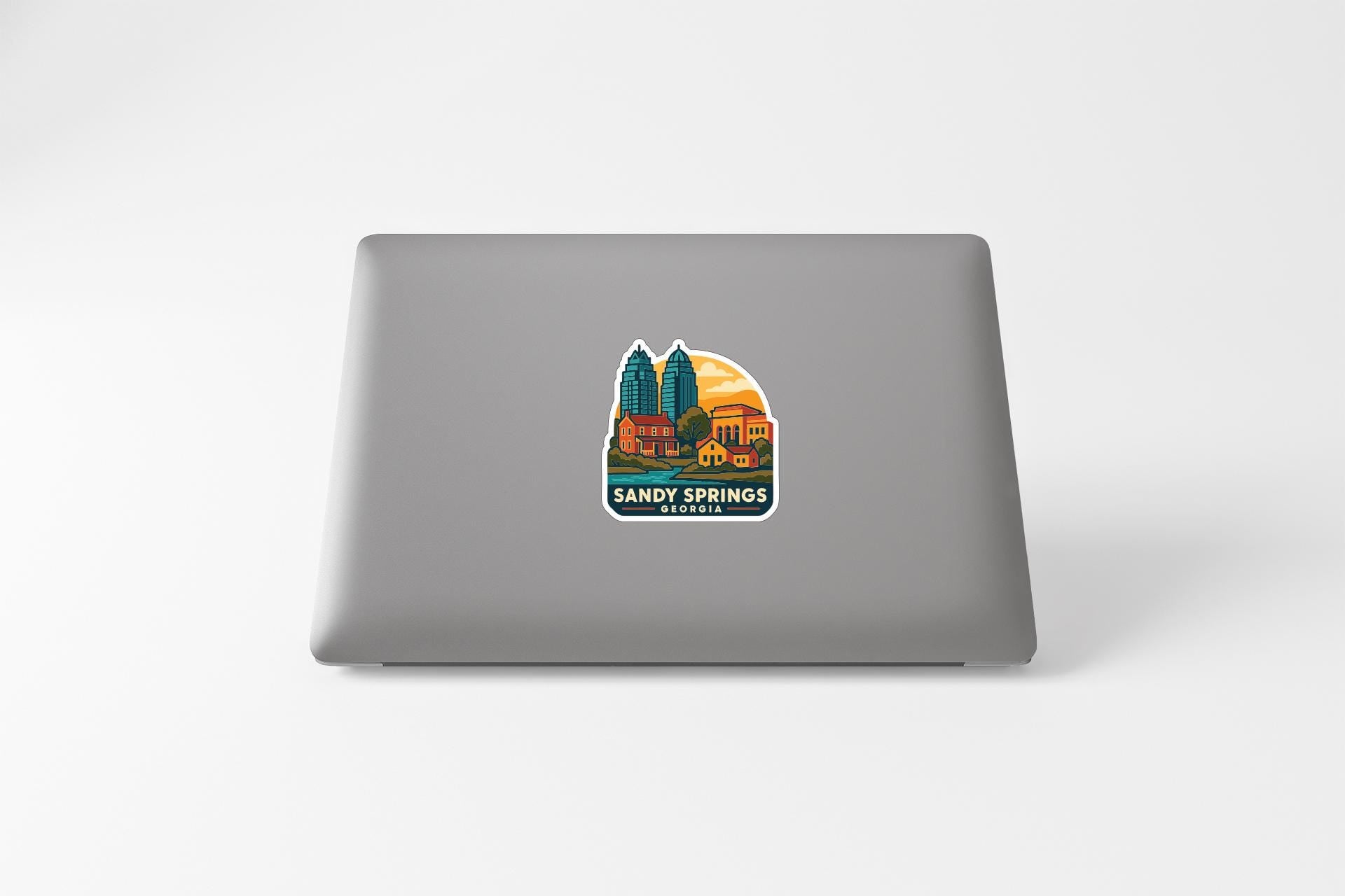 a sticker with a graphic of a city skyline and the text "SANDY SPRINGS GEORGIA" on the back of a laptop.