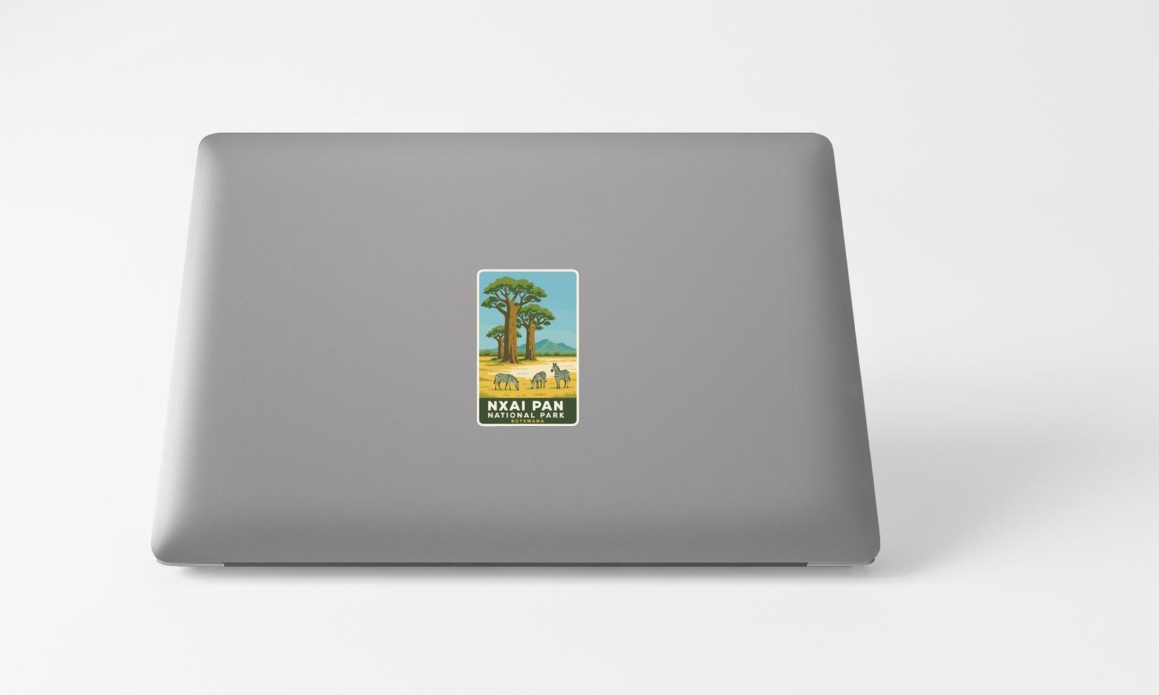 A sticker with an illustration of a tree and a bird is placed on the back of a laptop computer.