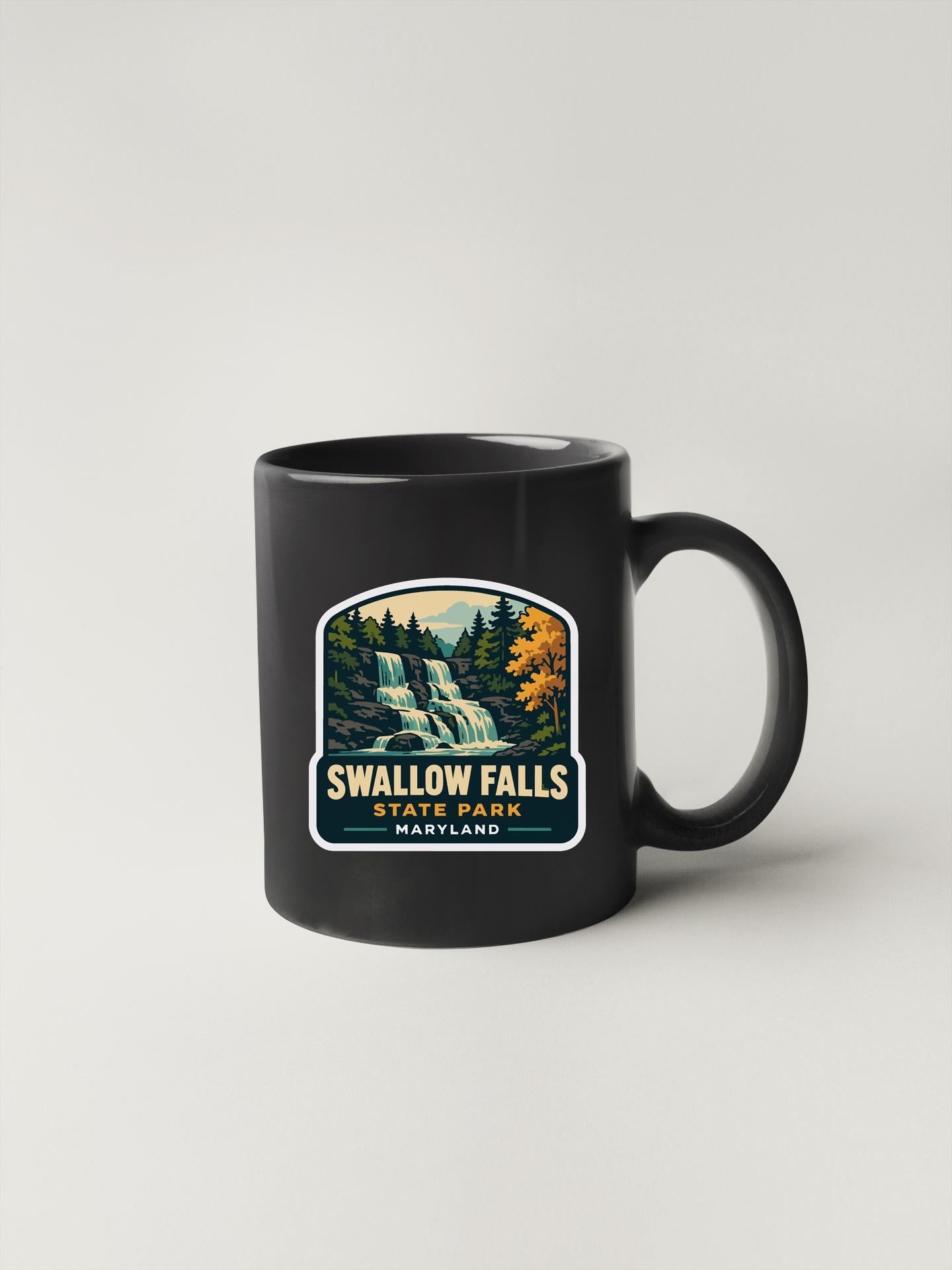 A black coffee mug with a graphic design depicting Swallow Falls State Park, Maryland.