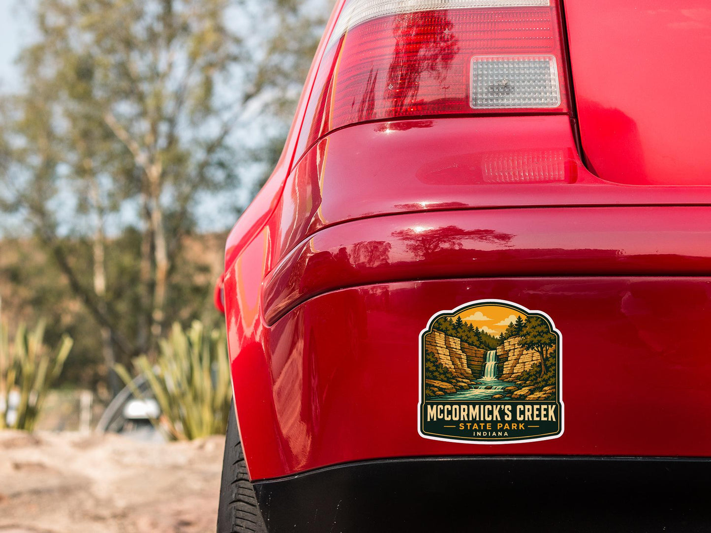 the rear end of a red car with a sticker on the trunk that reads "Mc Cormick's Creek State Park, Indiana".