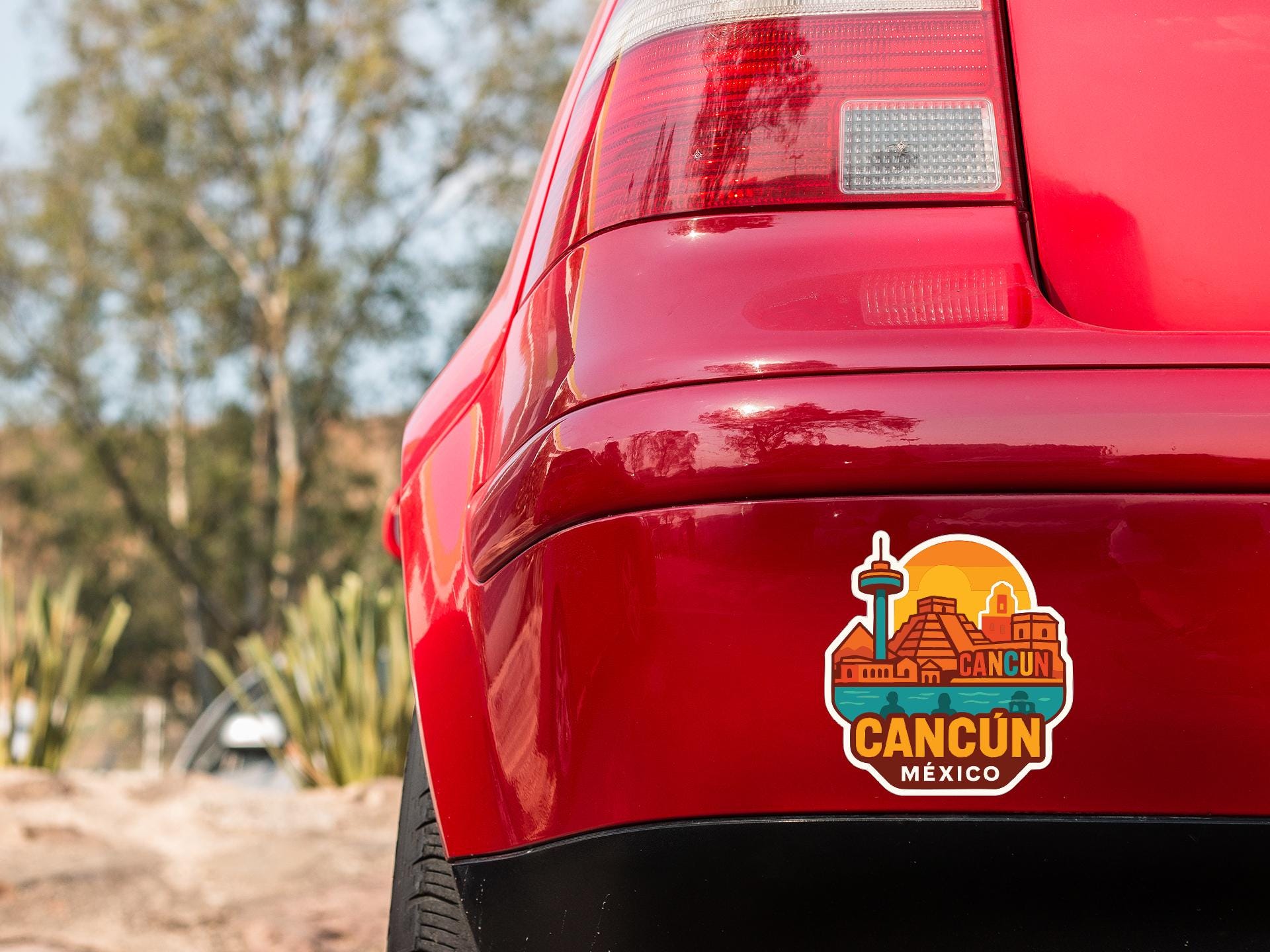 the rear end of a red car with a sticker on the trunk that features a cityscape of Cancun, Mexico.