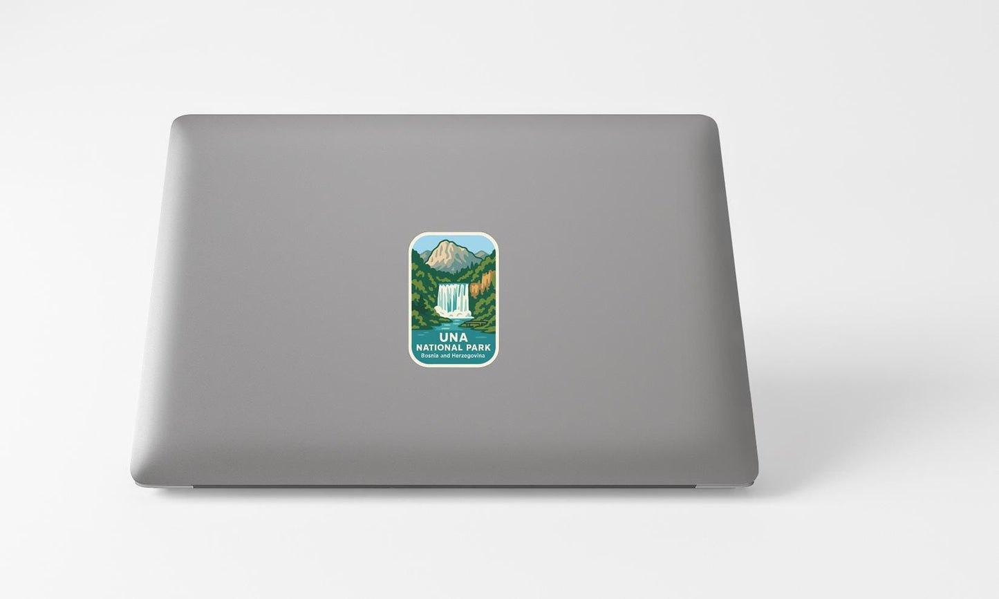 A sticker with a mountain landscape and waterfall on the back of a laptop computer.
