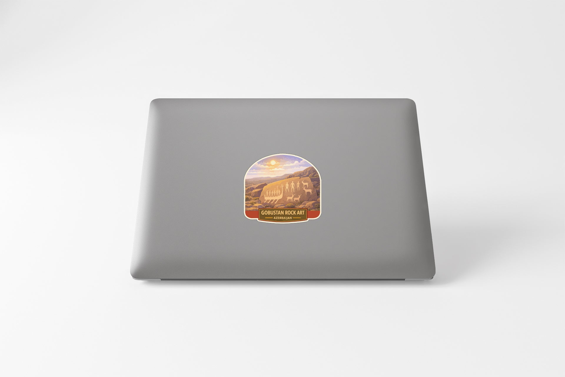 a sticker on the back of a laptop, depicting a scenic landscape with mountains and a sunset.