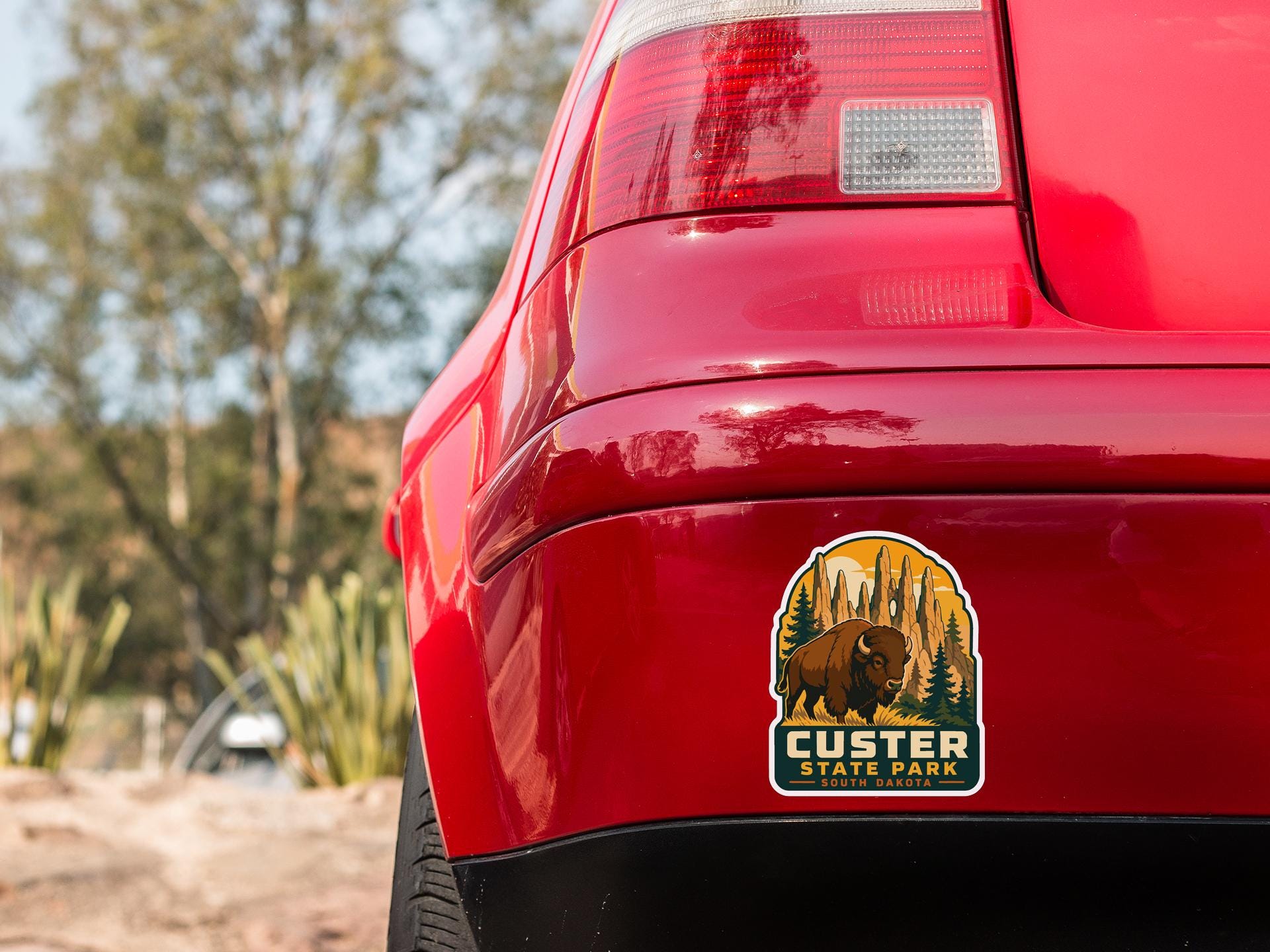 the rear end of a red car with a sticker on the trunk that says "CUSTER STATE PARK".