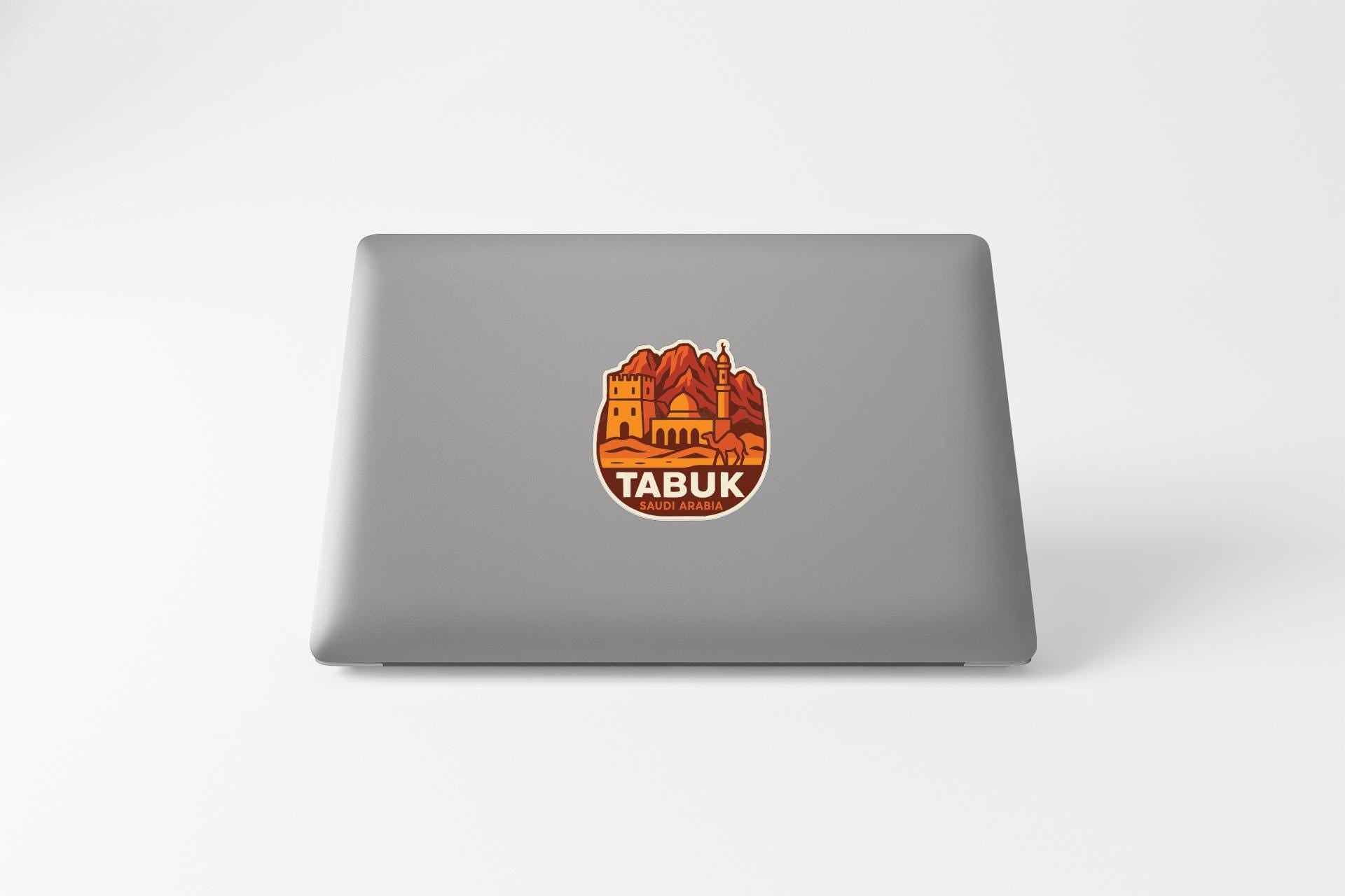 a sticker with an illustration of a landmark, likely Tabuk, on a laptop.