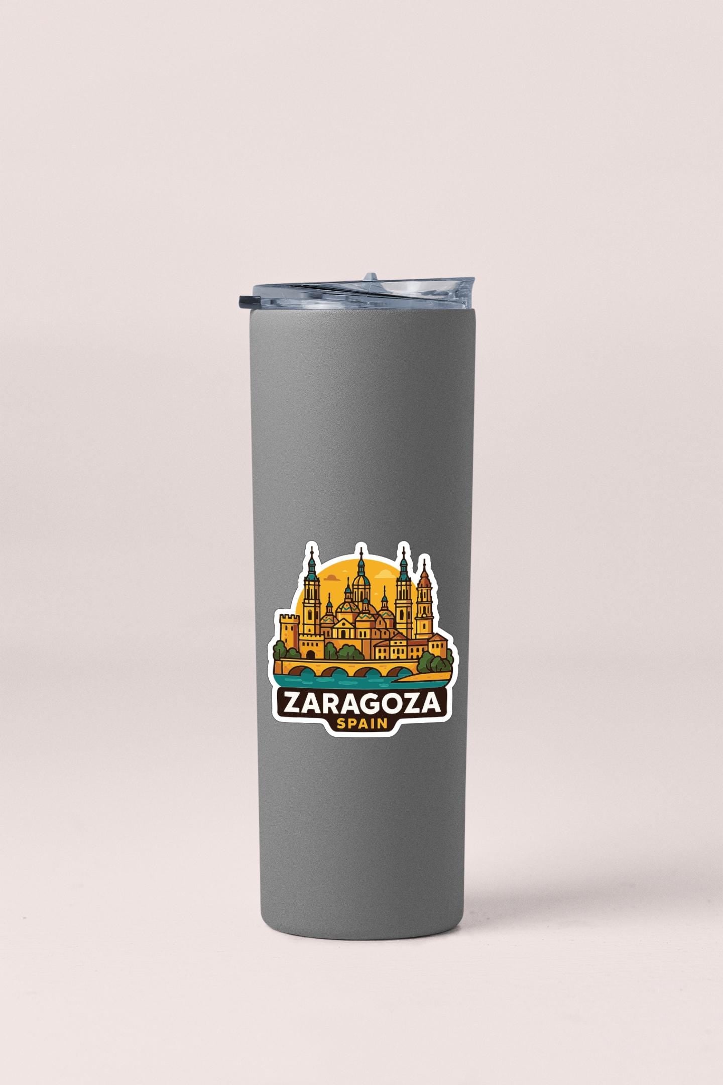 A gray insulated tumbler with a sticker depicting the Zaragoza skyline in Spain.