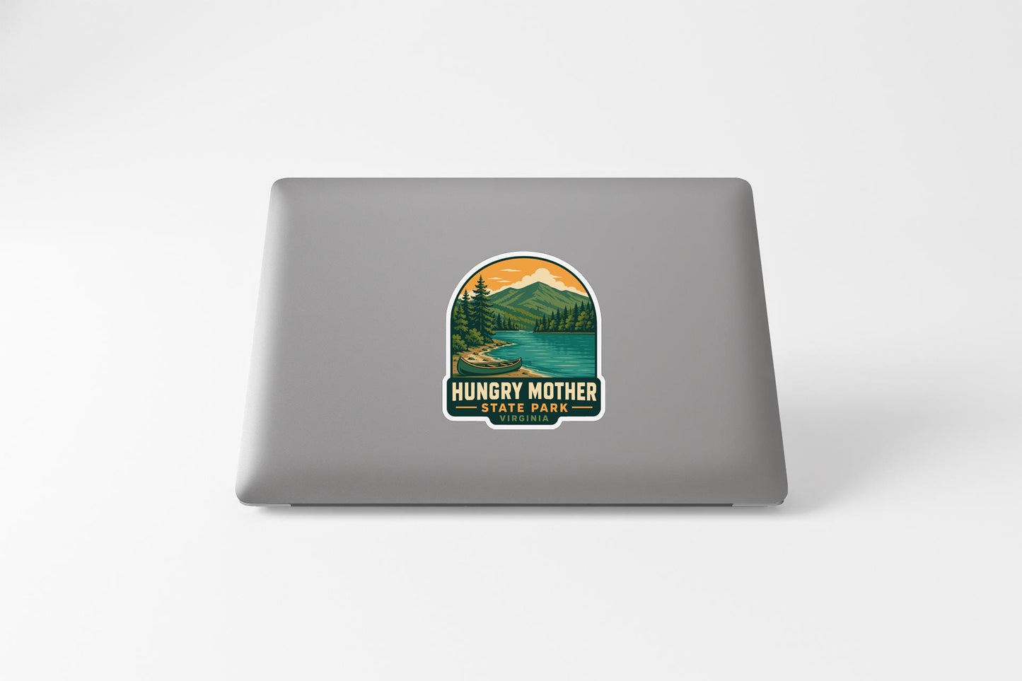 A sticker on the back of a laptop, depicting a scenic landscape with mountains, trees, and a lake.