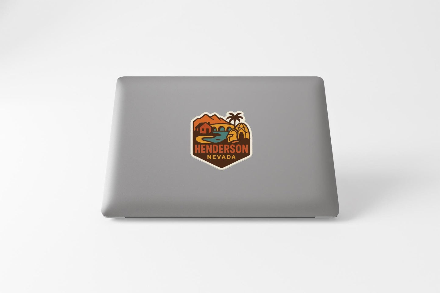 A sticker on the back of a laptop displaying the text "HENDERSON NEVADA" along with a colorful, vintage-style illustration of a desert landscape.