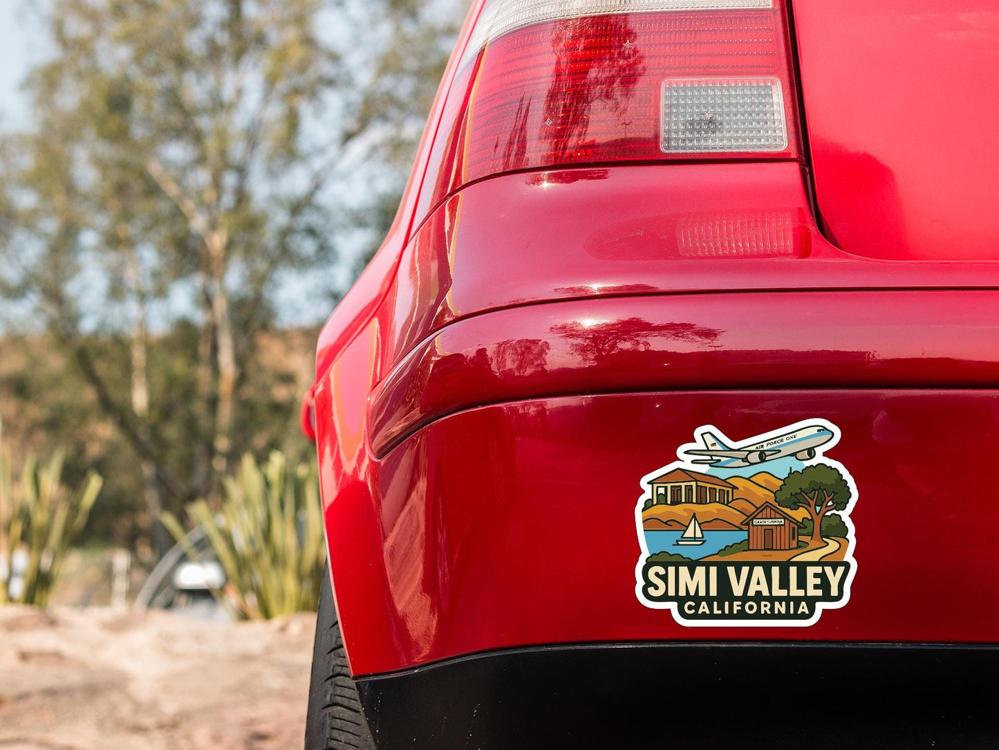 the rear end of a red car with a sticker on the trunk that says "SIMI VALLEY CALIFORNIA".