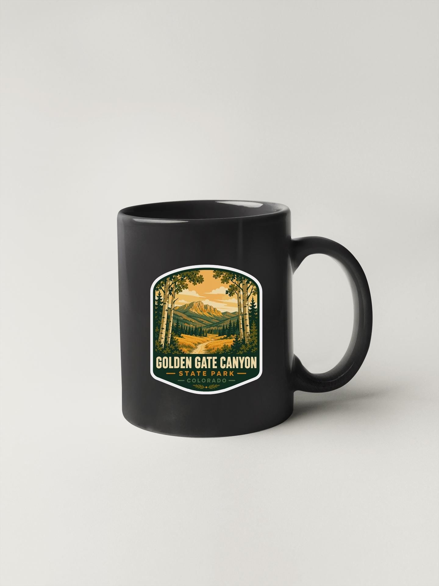 A black coffee mug with a label that says "Golden Gate Canyon State Park" and features an illustration of a scenic landscape.
