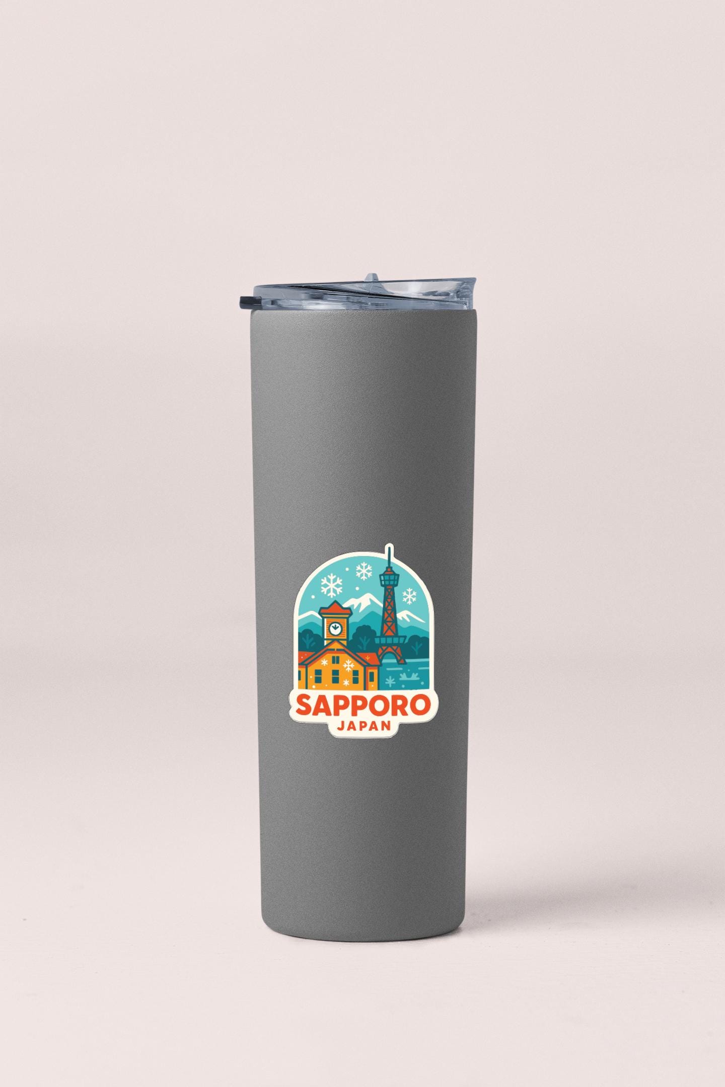 A gray insulated tumbler with a sticker depicting a cityscape and the text "SAPPORO JAPAN" printed on it.