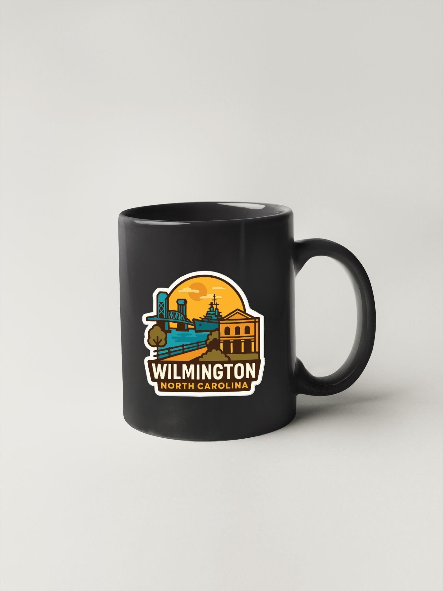 A black coffee mug with a graphic design depicting the city of Wilmington, North Carolina.