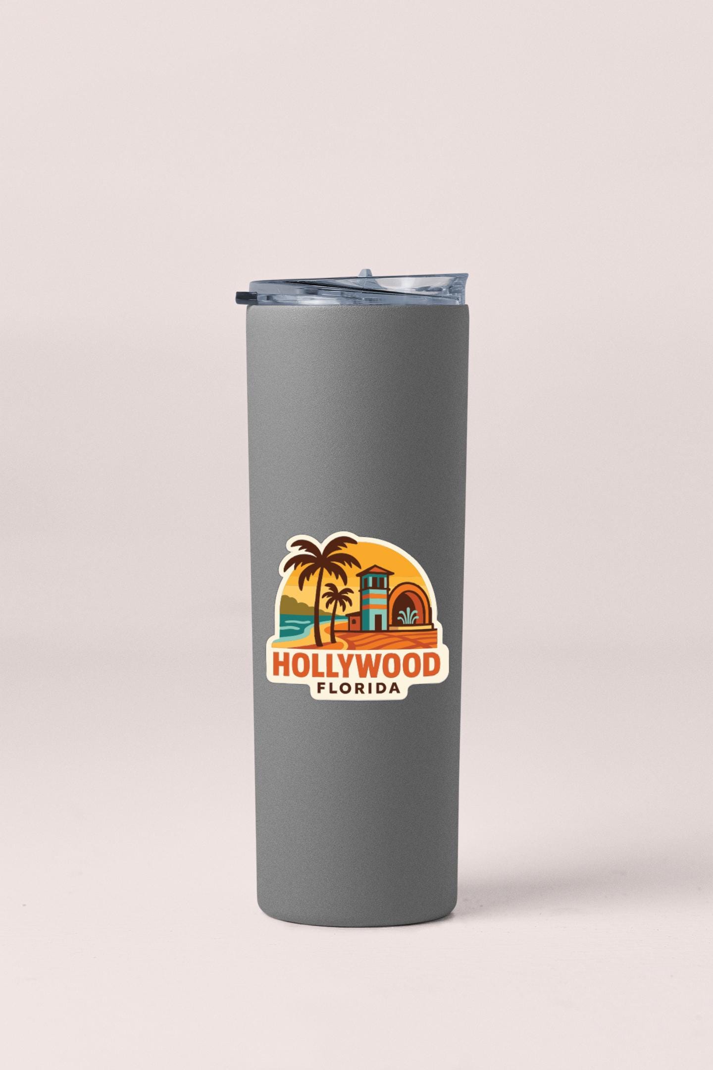 A gray tumbler with a sticker depicting a tropical beach scene and the text "Hollywood Florida" printed on it.