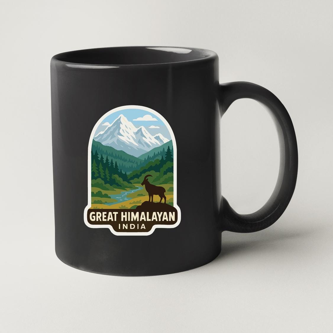A black coffee mug with a graphic design depicting a mountain landscape and a goat, along with the text "GREAT HIMALAYAN INDIA".