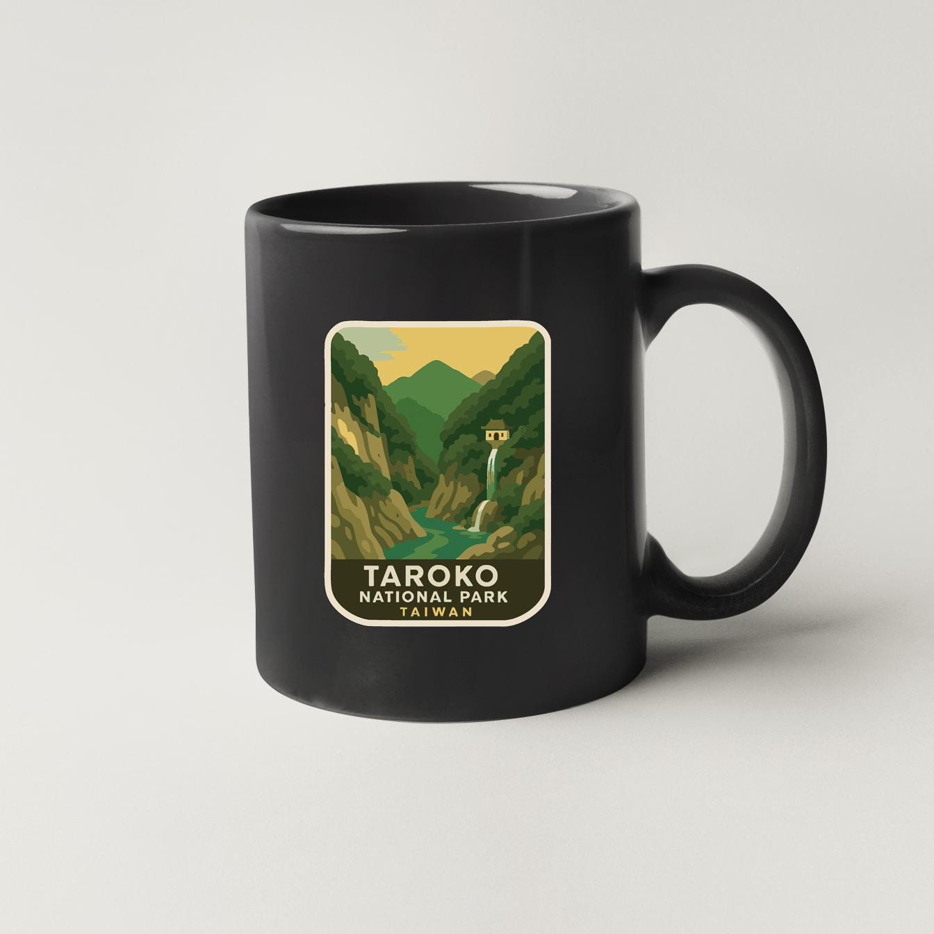 A black coffee mug with a label that says "TAROKO NATIONAL PARK" and features an illustration of a waterfall and mountains.
