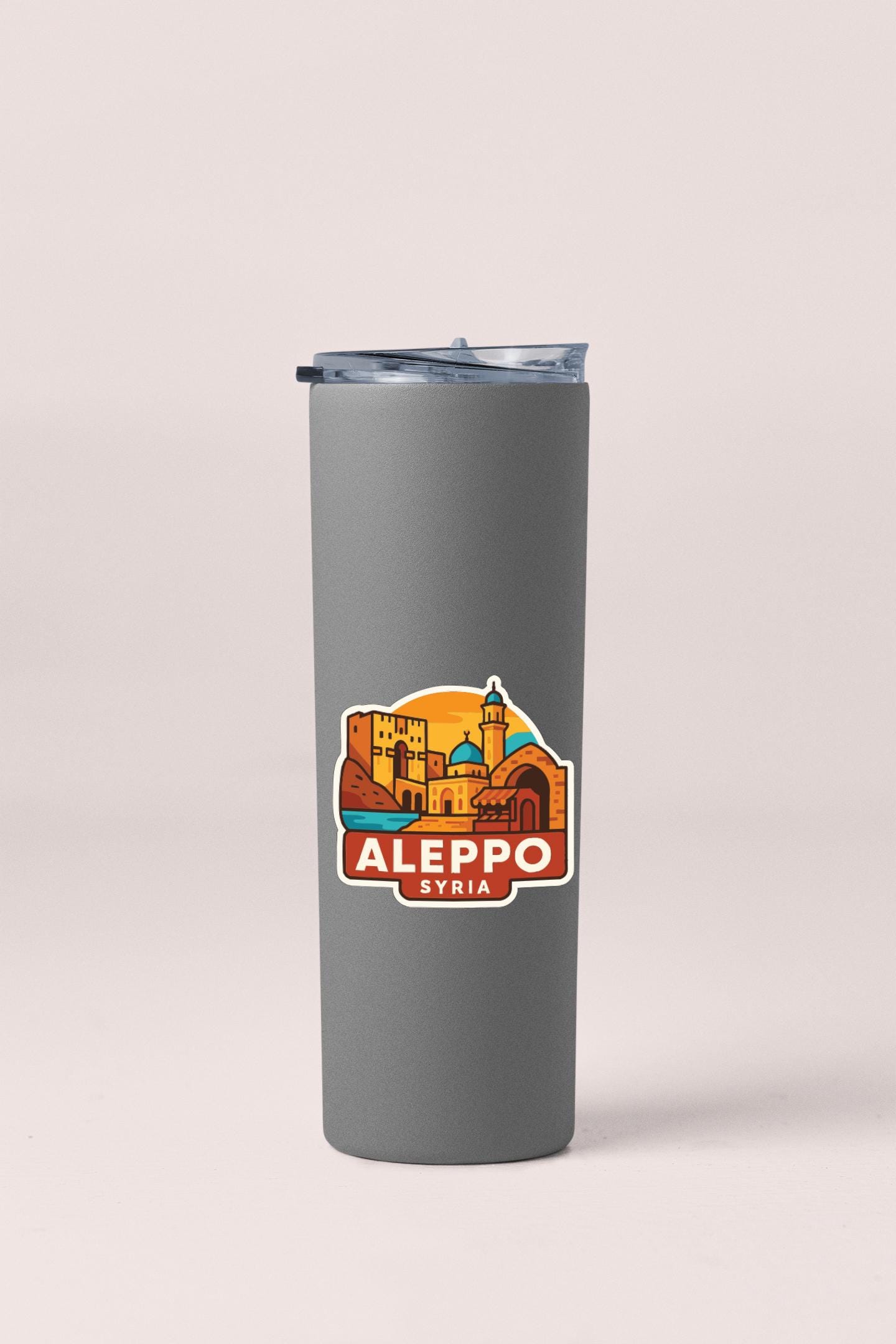 A gray insulated tumbler with a sticker depicting the city of Aleppo, Syria.