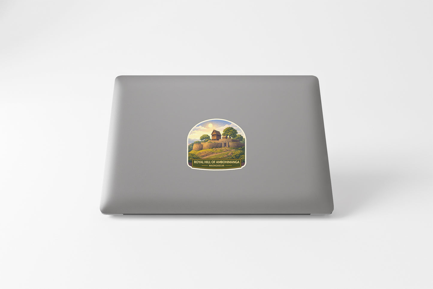 a sticker on the back of a laptop, depicting a castle or fortress surrounded by trees and hills.