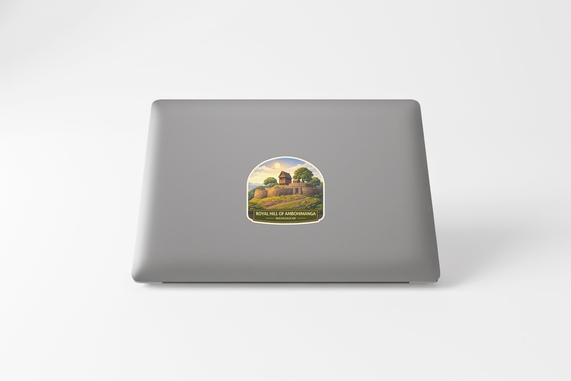 a sticker on the back of a laptop, depicting a castle or fortress surrounded by trees and hills.