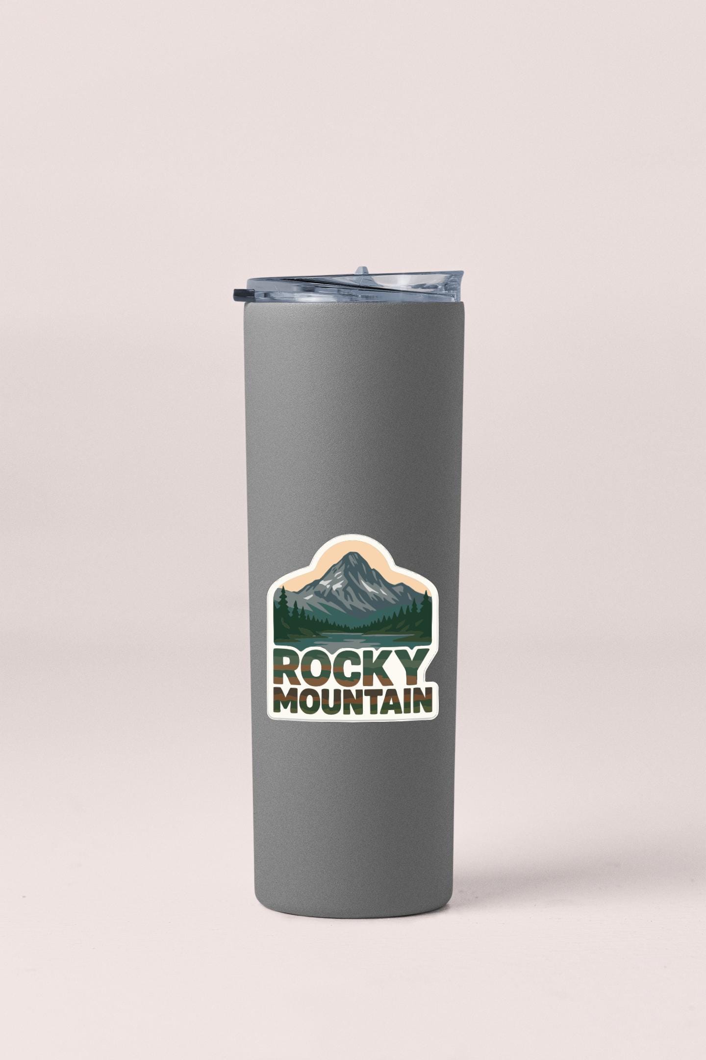 A gray insulated tumbler with a mountain landscape sticker on it.