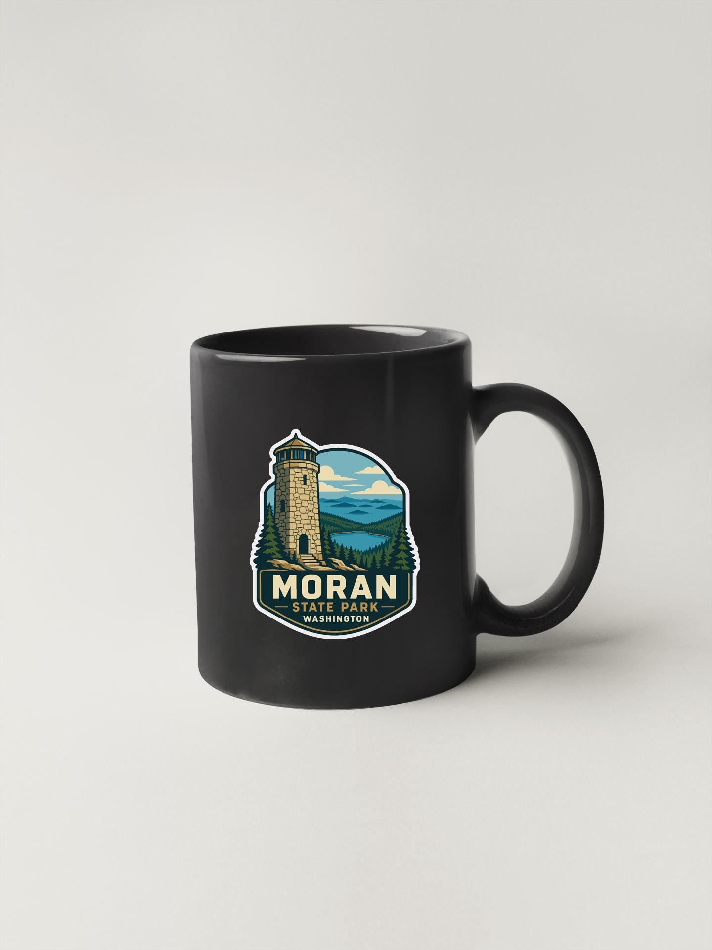 A black coffee mug with a graphic design featuring a tower and a scenic landscape.