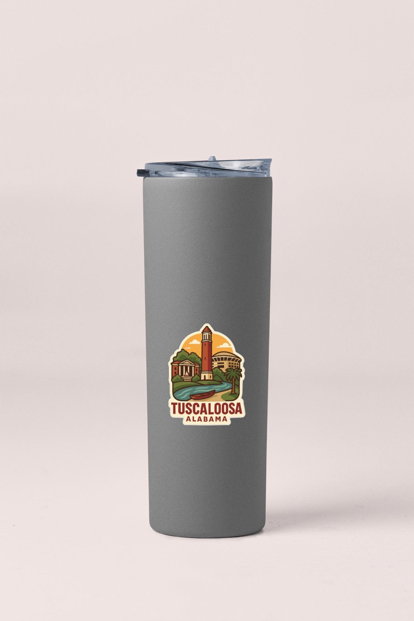 A gray insulated tumbler with a lid and a sticker depicting a landmark in Alabama.