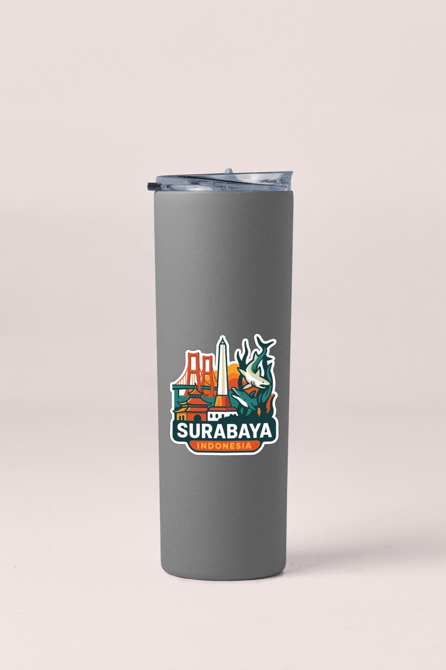 A gray insulated tumbler with a sticker featuring the city of Surabaya, Indonesia.